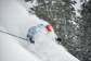 Male skier surrounded by powder snow while skiing.